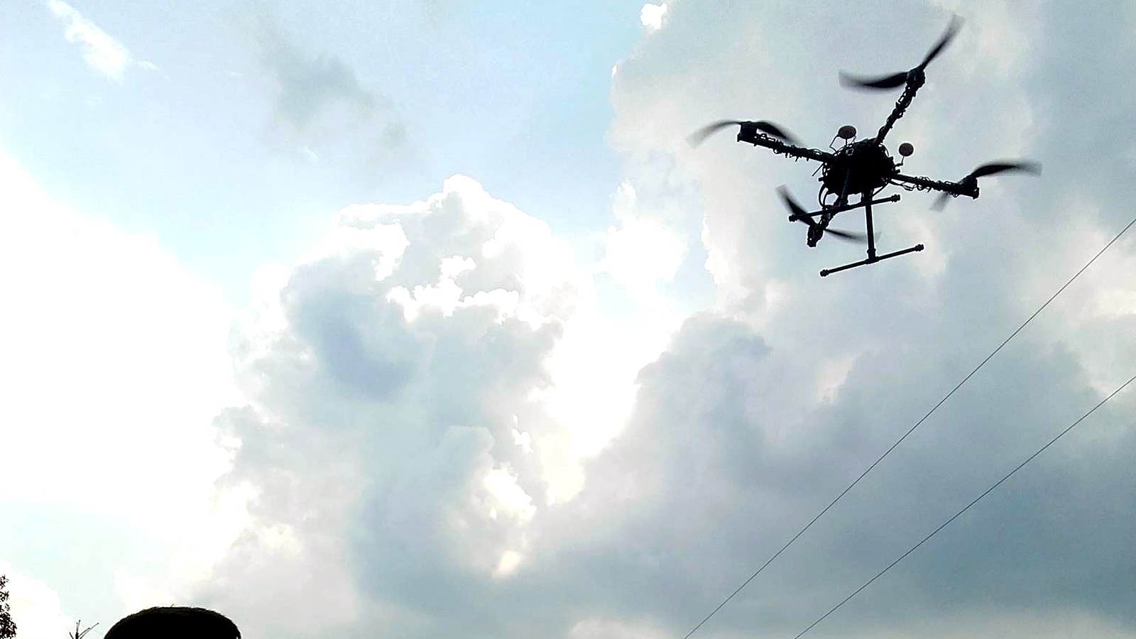 Quadcopter flying above the pilot during an outdoor flight test.
